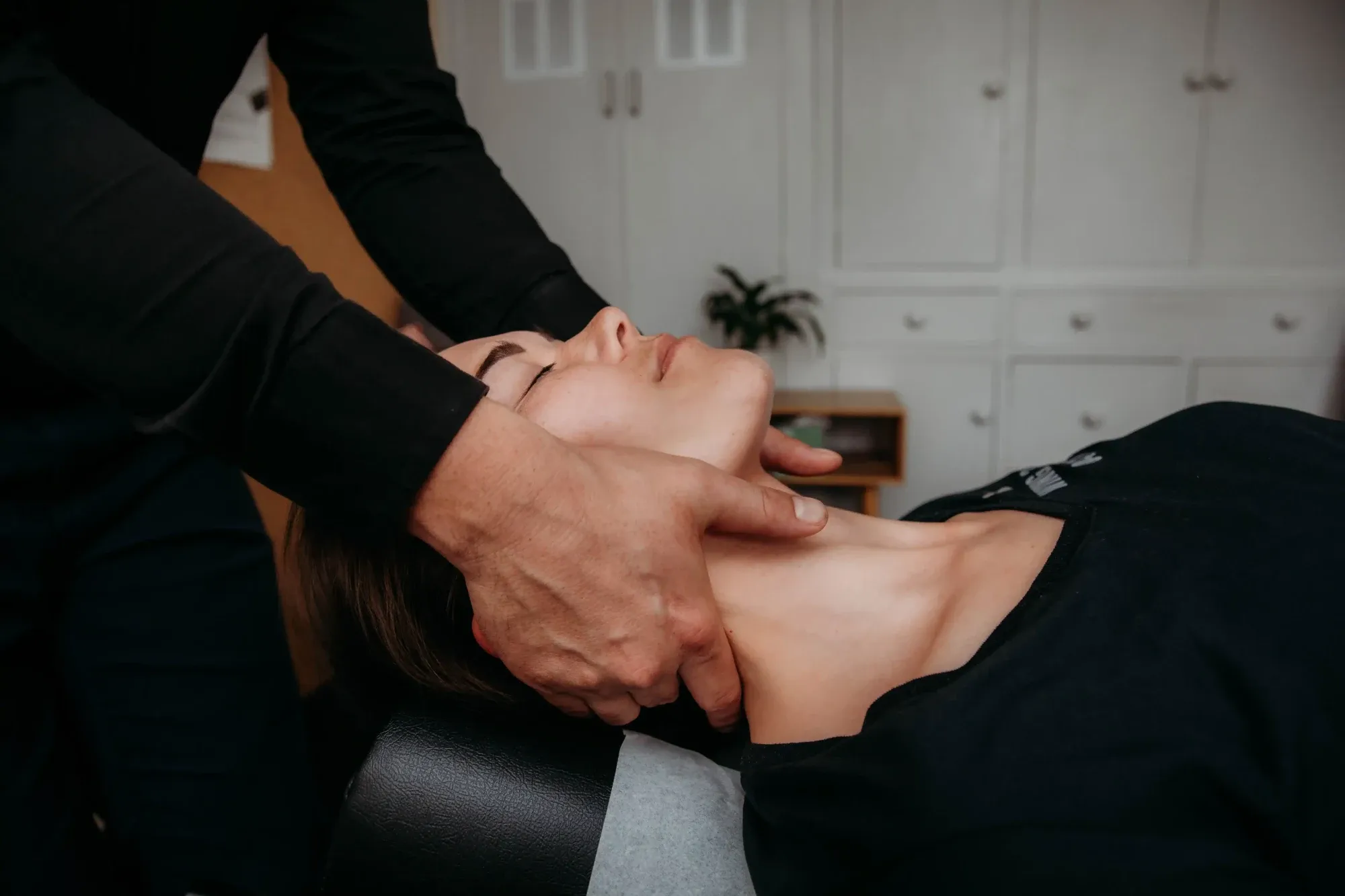 A chiropractor supporting a patient’s head and neck during an adjustment at the Hastings practice